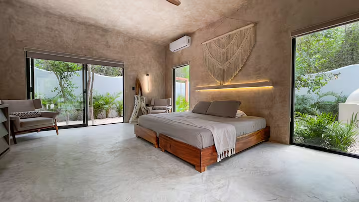 Tinez Suite — bedroom flanked by floor-to-ceiling windows opening to the garden