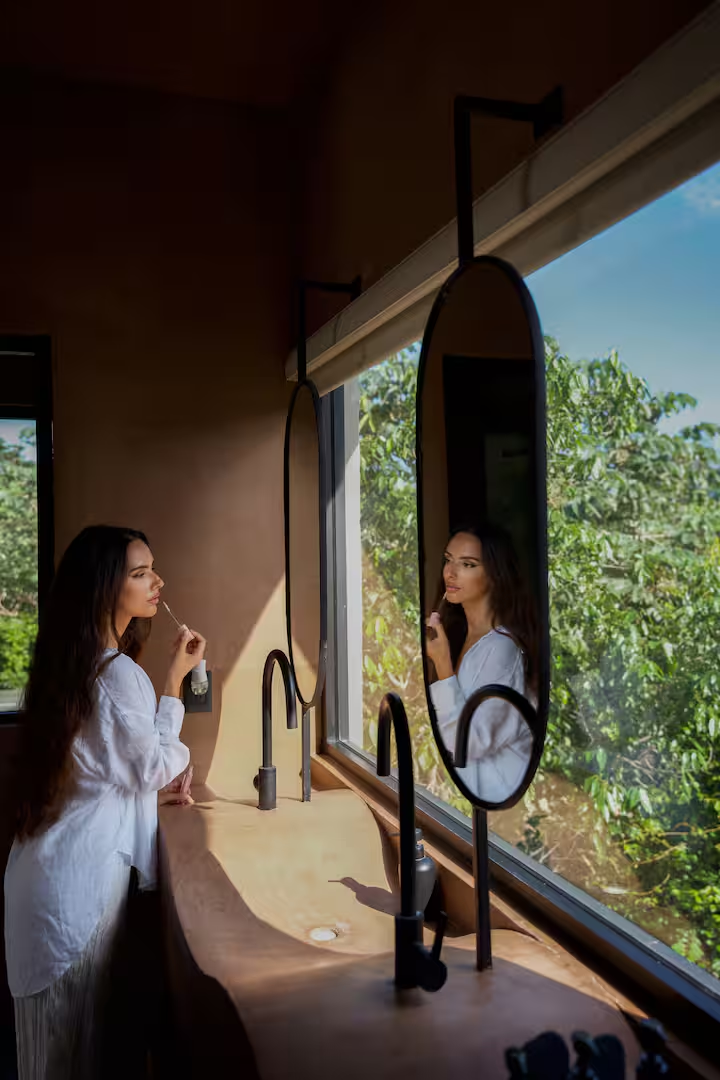 Revivis Suite — sunlit vanity with oval mirrors and jungle view