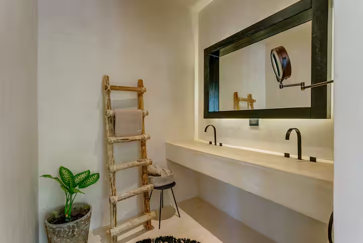 Cajmere Suite — double vanity with black-framed mirror and ladder towel rack