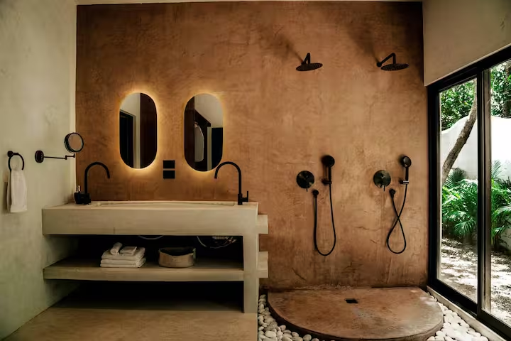 Tinez Suite — terracotta bathroom with dual rainshowers and backlit oval mirrors