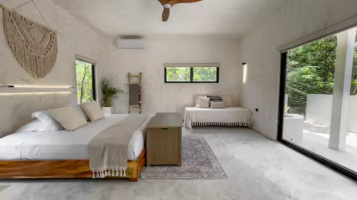 Okain Suite — king bed and single bed with macramé wall hanging and jungle views