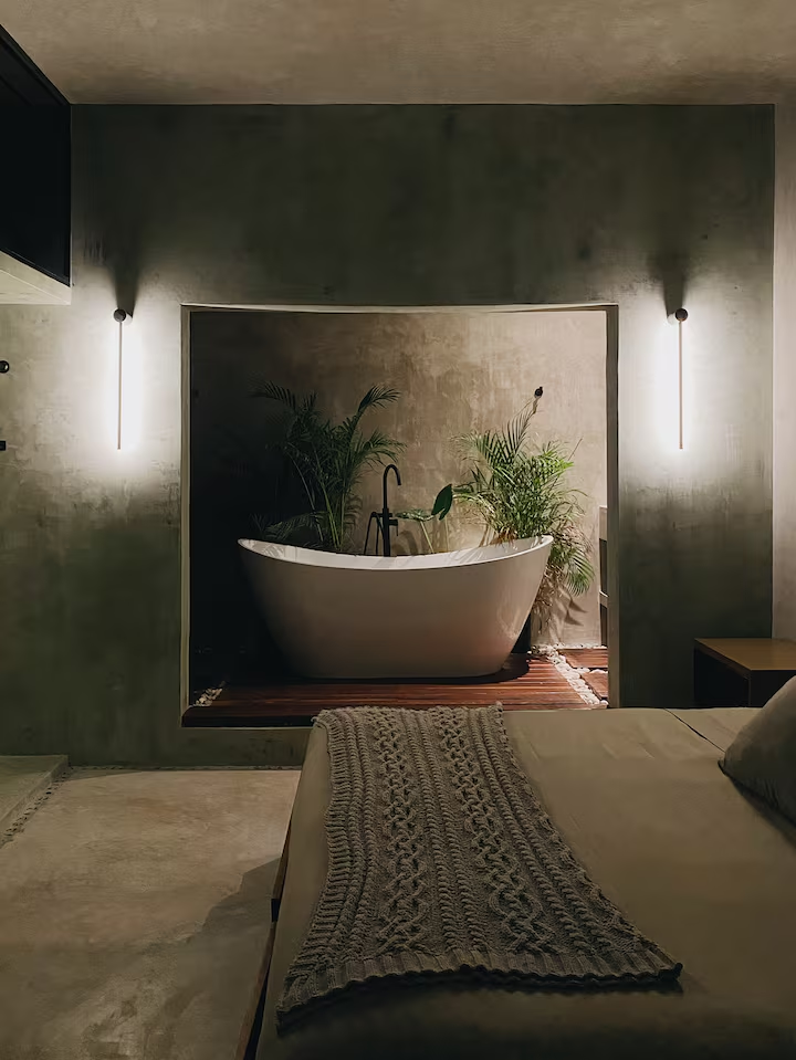 Tirzah Suite — freestanding tub framed by linear sconces at night