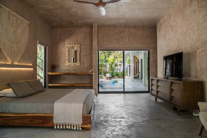 Tinez Suite — king bed with macramé wall hanging and sliding doors to private pool